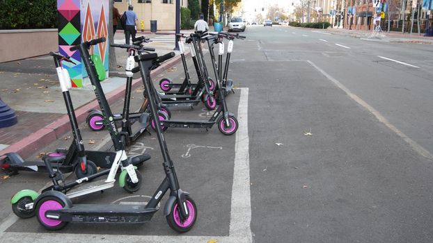 SAN DIEGO, CALIFORNIA USA - 4 JAN 2020: Row of ride sharing electric scooters parked on street in Gaslamp Quarter. Rental dockless public bikes, eco transport in city. Rent kick cycle with mobile app.