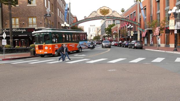 SAN DIEGO, CALIFORNIA USA - 30 JAN 2020: Gaslamp Quarter historic entrance arch sign on 5th avenue. Orange iconic retro trolley, hop-on hop-off bus and tourist landmark, Old Town Sightseeing Tour.