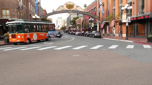 SAN DIEGO, CALIFORNIA USA - 30 JAN 2020: Gaslamp Quarter historic entrance arch sign on 5th avenue. Orange iconic retro trolley, hop-on hop-off bus and tourist landmark, Old Town Sightseeing Tour.