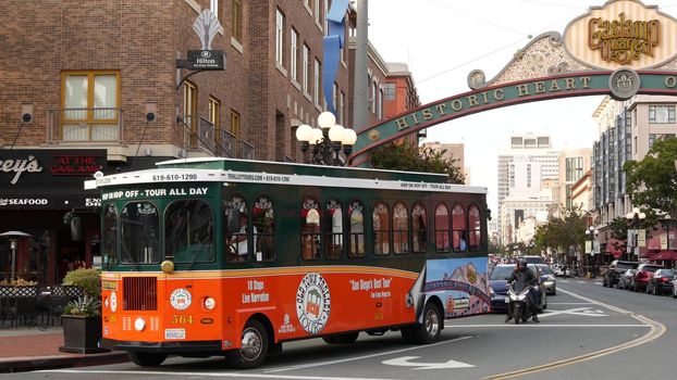 SAN DIEGO, CALIFORNIA USA - 30 JAN 2020: Gaslamp Quarter historic entrance arch sign on 5th avenue. Orange iconic retro trolley, hop-on hop-off bus and tourist landmark, Old Town Sightseeing Tour.