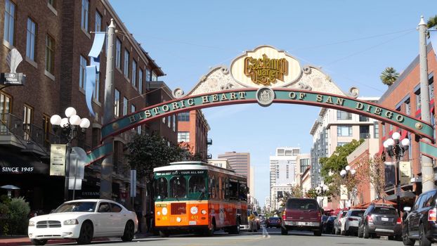 SAN DIEGO, CALIFORNIA USA - 13 FEB 2020: Gaslamp Quarter historic entrance arch sign on 5th avenue. Orange iconic retro trolley, hop-on hop-off bus and tourist landmark, Old Town Sightseeing Tour.