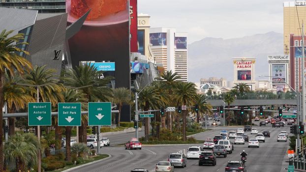 LAS VEGAS, NEVADA USA - 7 MAR 2020: The Strip boulevard with luxury casino and hotels in gambling sin city. Car traffic on road to Fremont street in tourist money playing resort. People on sky bridge.