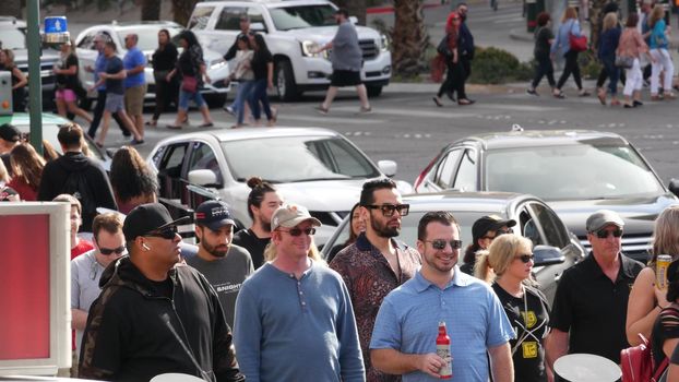 LAS VEGAS, NEVADA USA - 7 MAR 2020: People on pedestrian walkway. Multicultural men and women walking on city promenade. Crowd of citizens on sidewalk. Diversity of multiracial faces in metropolis.