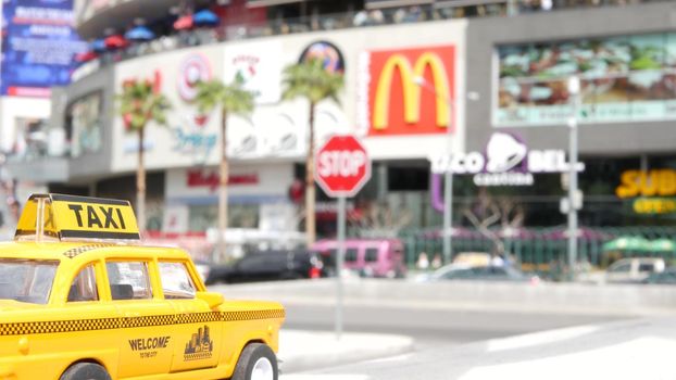 LAS VEGAS, NEVADA USA - 7 MAR 2020: Yellow vacant mini taxi cab close up on Harmon avenue corner. Small retro car model. Little iconic auto toy as symbol of transport against american shopping mall.