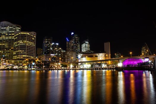 Night City Skyline of Darling Harbour, Australia, with light reflection on calm water.