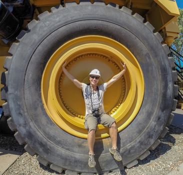 Tire of a earth moving dump truck with a man in the wheel for scale