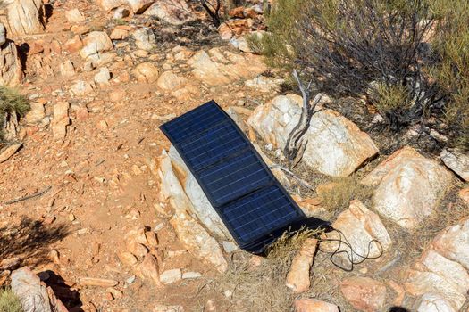 solar panel in campsite on a rock to charge phones and camera, alternative electricity source