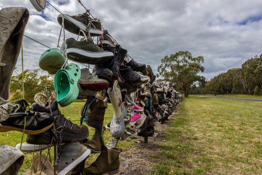Old shoes on a fence next to a road in Australia. tourist put their old shoes on the fence.