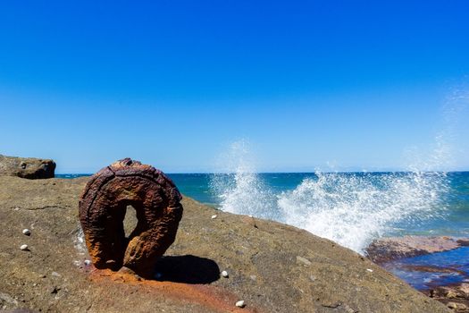 an old rusty round hook from the historic Sea Clliff Bridge with waves in the background, along the Grand Pacific Drive, Australia