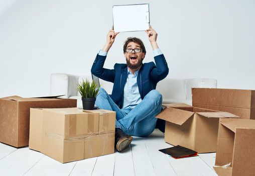 Emotional Man sits on the floor next to boxes unpacking a move Professional. High quality photo