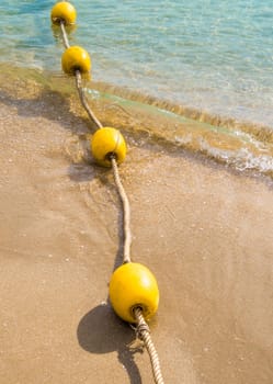 Floating buoy and rope dividing the area on the beach