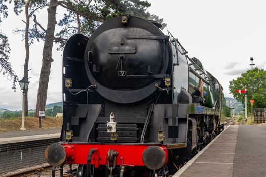 An old iron steam locomotive in a countryside station