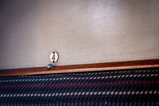 Close-up of a wall with a grid pattern and a metal plaque with the number four in an old train