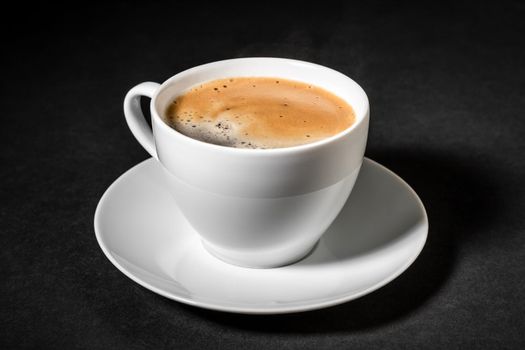 White cup of fresh black coffee on a dark background close-up