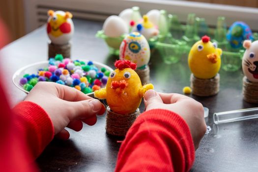 The child finishes making another egg-shell figurine to celebrate Easter