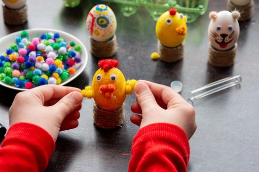 Children's hands made a chicken craft out of an egg, there are other figures in the background