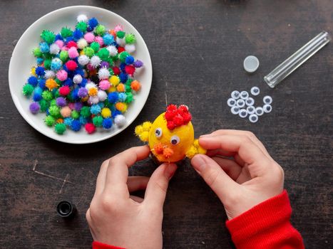 Childrens hands make chicken from eggshell for easter holiday, top view