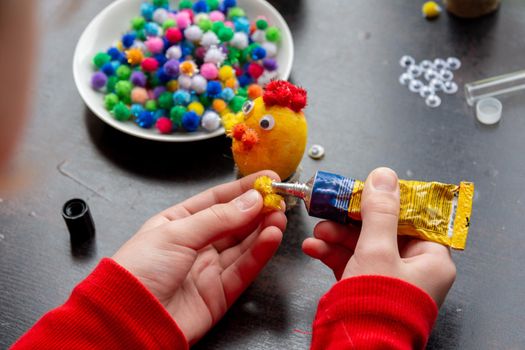 Child's hands make a chicken-shaped egg shell craft