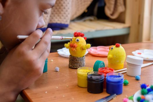 Girl gently paints Easter eggs with a brush and paints