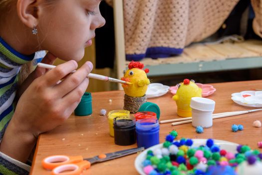 The girl paints crafts from eggs for the Easter holiday
