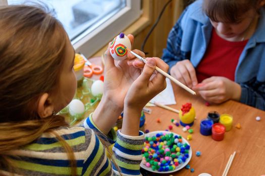 Children at the table are painting Easter eggs for the holiday