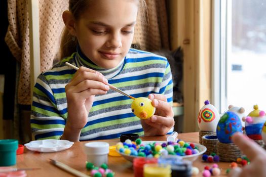 A twelve-year-old girl paints Easter eggs for the holiday