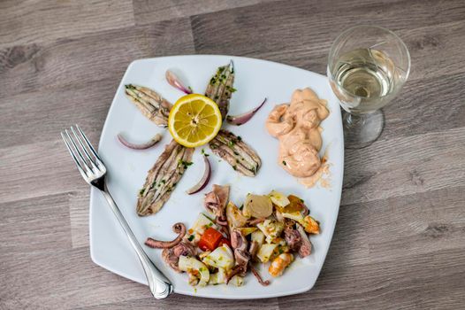 appetizer with seafood goblet of wine and cutlery on wooden background