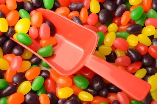 A closeup view of a red scoop in an abundant supply of jelly bean candy.