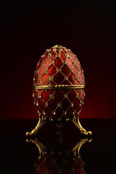 A faberge style egg focused over a dark red and black gradient background.