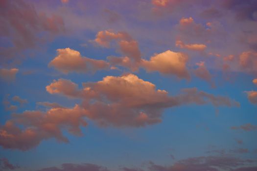 magical pink clouds at sunset on background of blue sky.