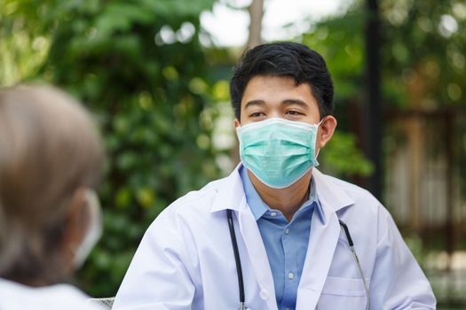 Asian doctor talking with elderly female patient on wheelchair