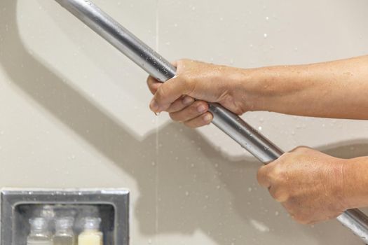 Senior woman holding on handrail for safety in bathroom