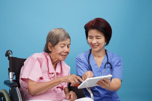 Asian nurse talking with elderly female patient on wheelchair