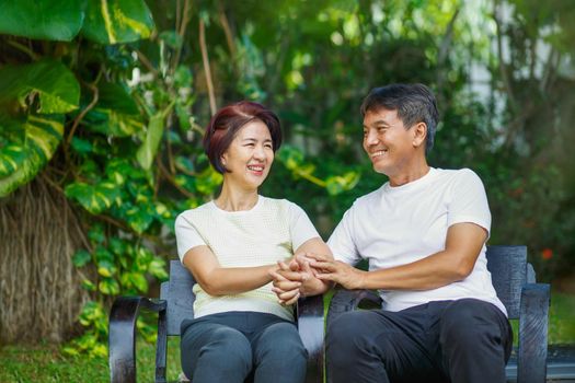 Middle aged couple relax sitting on bench in backyard.