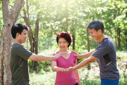 Father mother and adult son exercise in the park