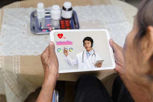 Elderly woman sit at home having online consultation with doctor on tablet computer.