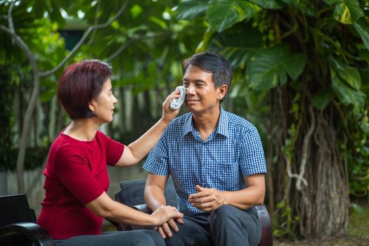 Middle aged couple relax sitting on bench in backyard.