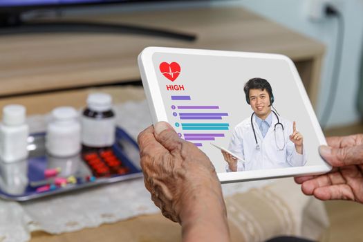 Elderly woman sit at home having online consultation with doctor on tablet computer.