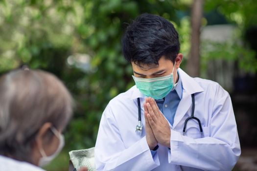 Thai Doctor greeting (wai) senior patient in wheelchair