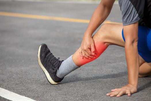 Male middle aged having a cramp while jogging. Stop and massage calf