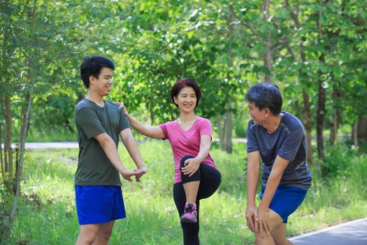 Father mother and adult son exercise in the park