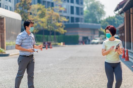 Asian middle aged people wearing mask and keep social distancing to avoid the spread of COVID-19