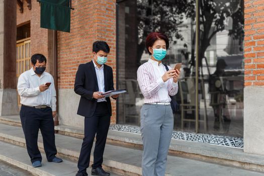 Asian middle aged people wearing mask and keep social distancing to avoid the spread of COVID-19