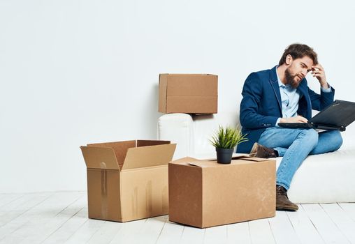 Business man sitting on the couch with laptop boxes with things unpacking office official. High quality photo