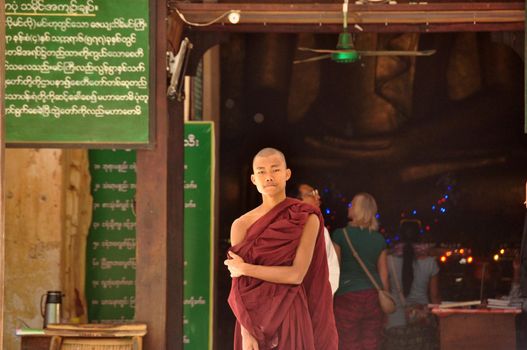 BAGAN, MYANMAR - NOV 13, 2015: Ethnic monk portrait. Young Asian man in robe of monk standing in front of temple entrance. Mingalazedi pagoda. Sulamani Shwezigon Ananda Htilominlo