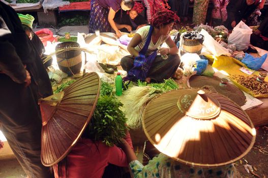 INLE, MYANMAR - NOVEMBER 29, 2015: Green local lake market in sunlight, Ethnic poor asian tribe people on local market with natural goods.