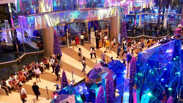 BANGKOK, THAILAND - 18 DECEMBER, 2018: Siam Paragon asian shopping mall interior. Crowds of people near the entrance of trade centre. people rush for New Year's shopping among the scenery