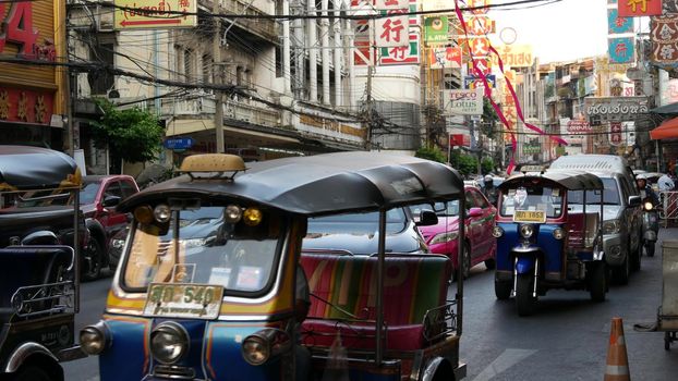 BANGKOK, THAILAND - 18 MARCH, 2019: Tuk tuks on street of Asian city. Colorful auto rickshaws riding on asphalt road on busy street of Chinatown in Bangkok