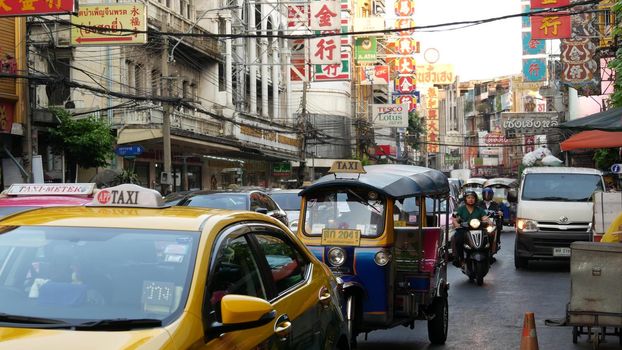 BANGKOK, THAILAND - 18 MARCH, 2019: Tuk tuks on street of Asian city. Colorful auto rickshaws riding on asphalt road on busy street of Chinatown in Bangkok