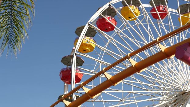 SANTA MONICA, LOS ANGELES, USA - 28 OCT 2019: Iconic colorful retro ferris wheel, roller coaster in amusement park. Famous classic california summertime symbol, pier of pacific ocean beach resort.